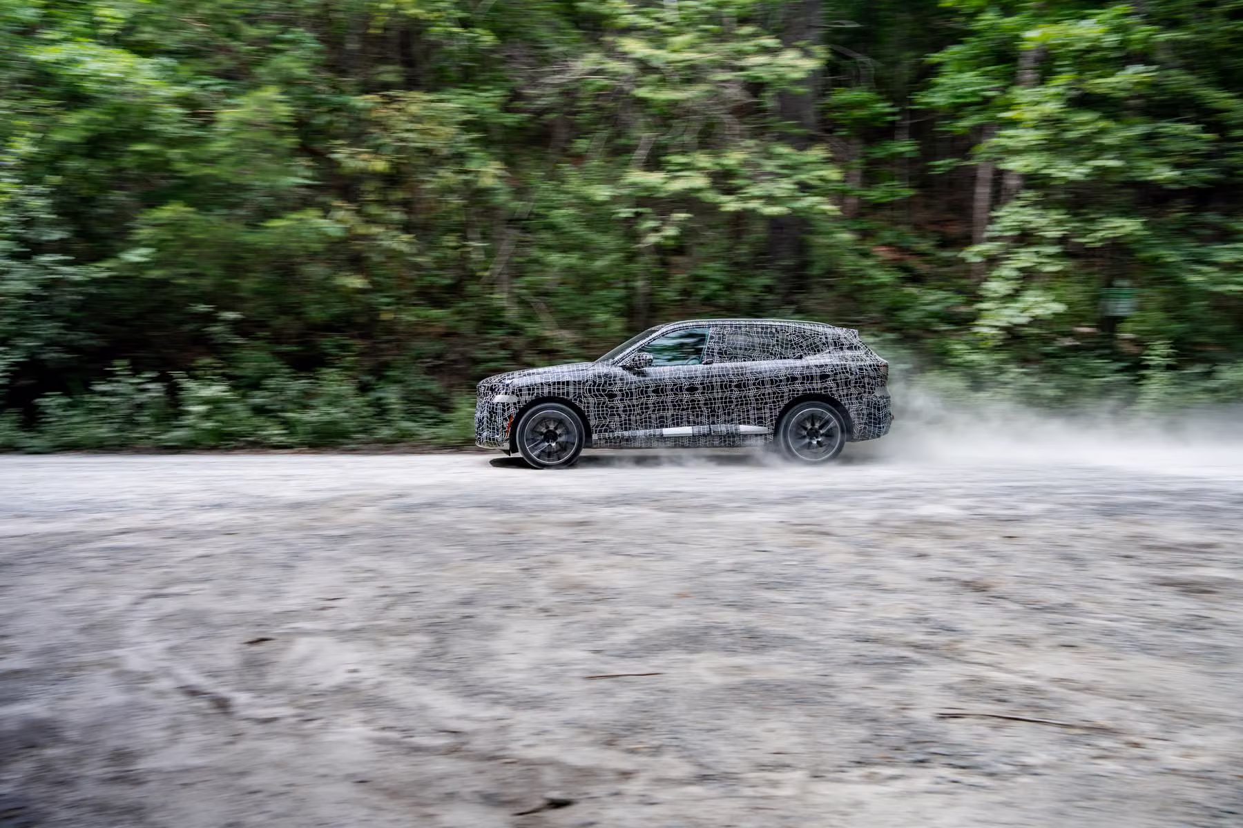 Novo BMW X5 camuflado cruzando trecho molhado ou de baixa aderência