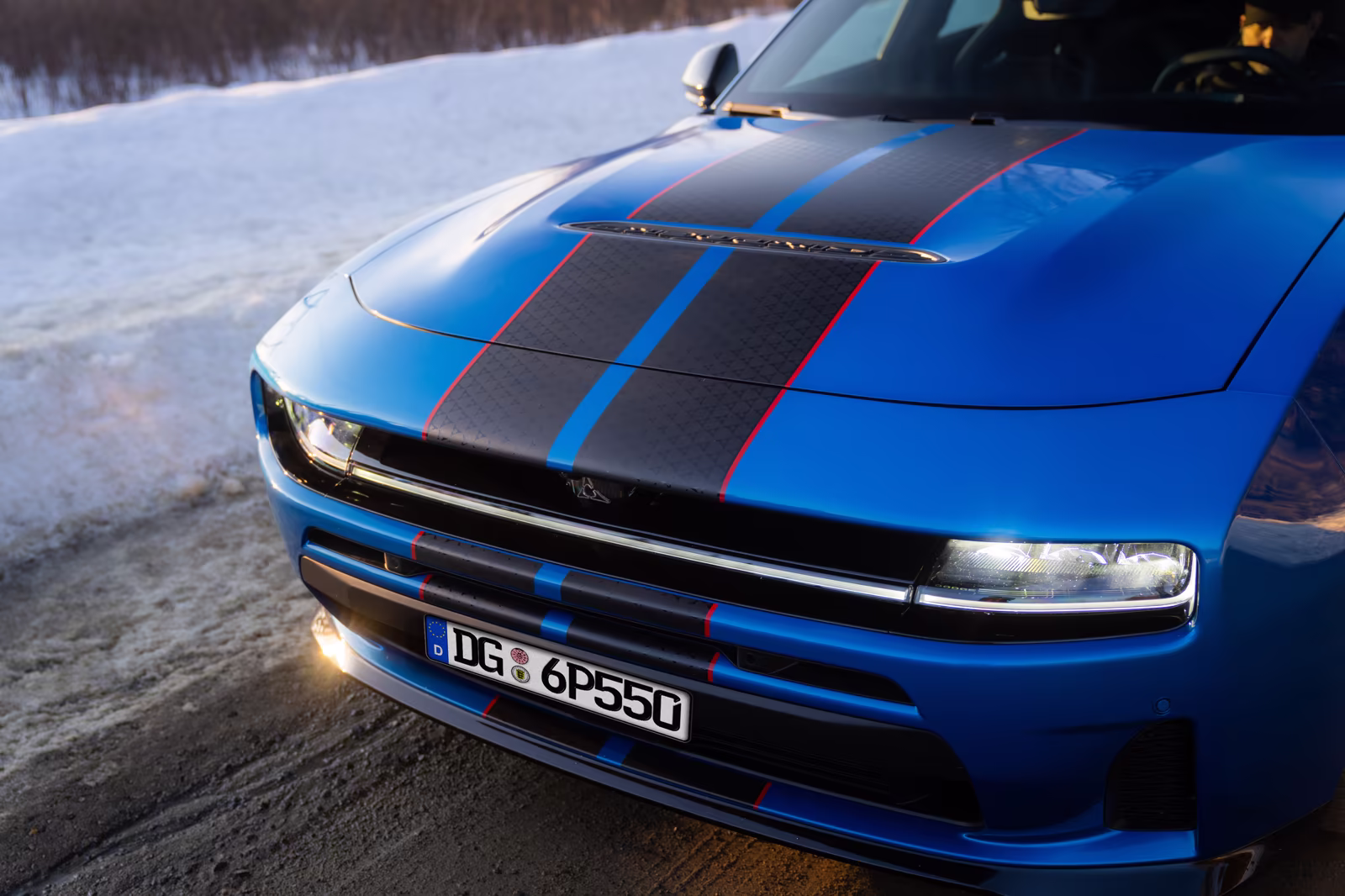 Dodge Charger azul em imagem frontal oficial na neve com capô longo e assinatura luminosa