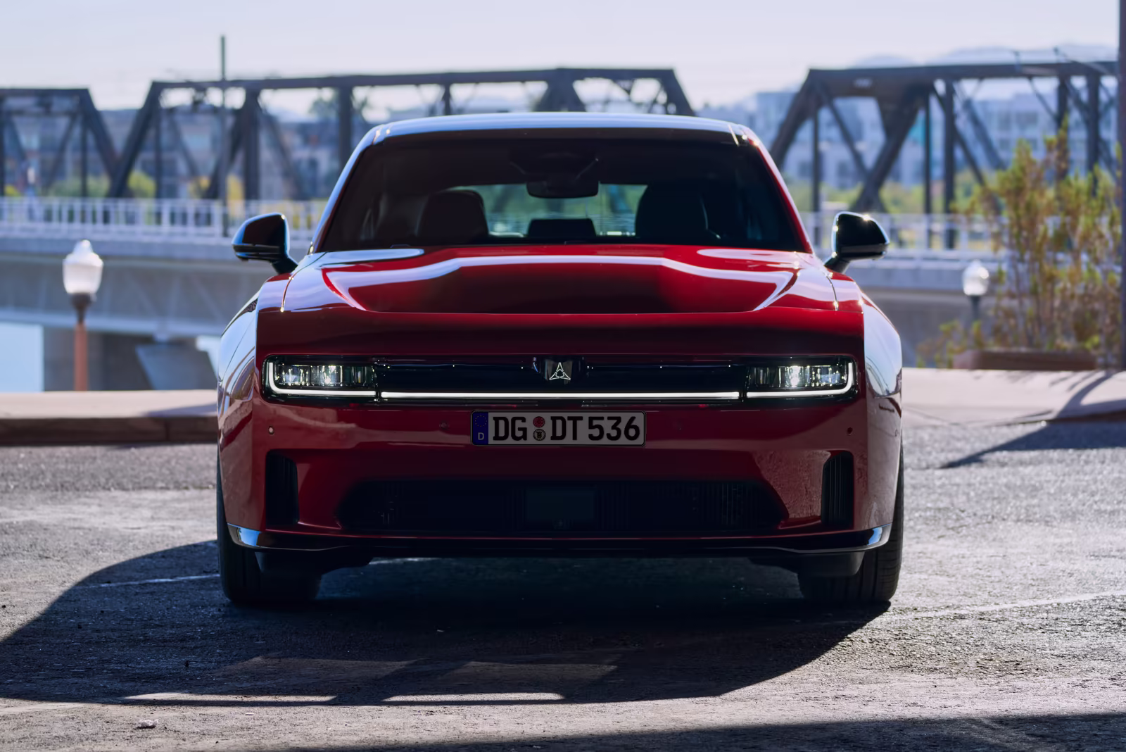 Dodge Charger vermelho visto de frente com ponte ao fundo