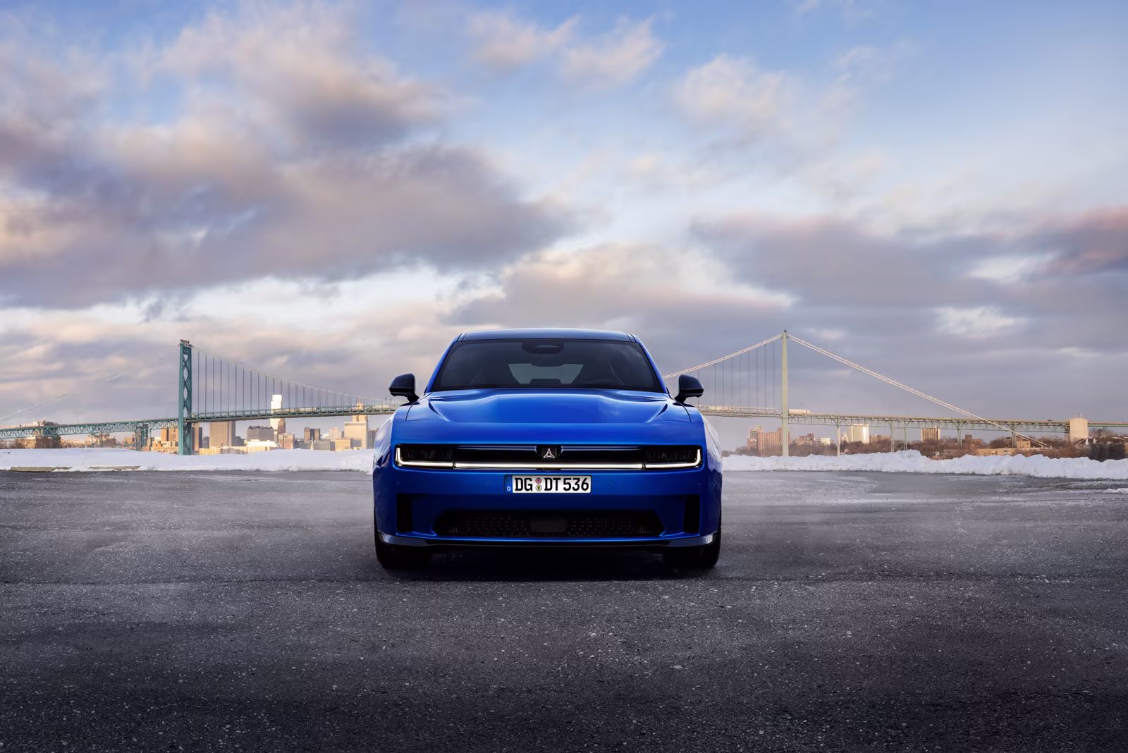 Dodge Charger azul de frente com ponte ao fundo em imagem oficial