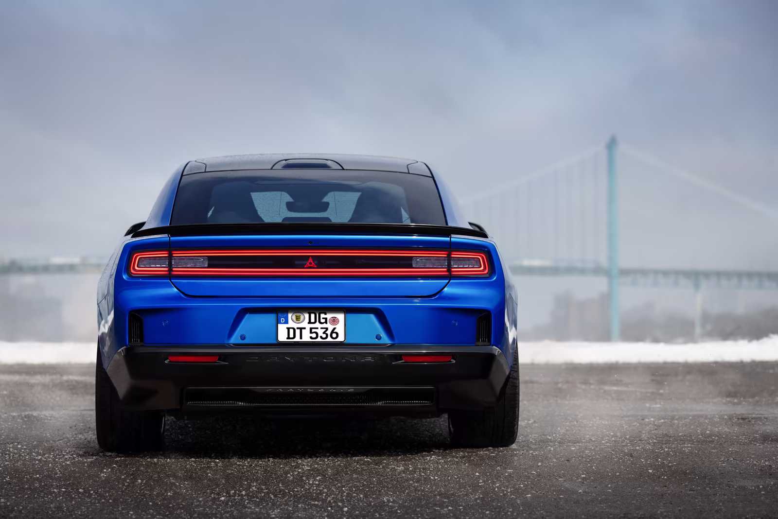 Dodge Charger azul visto por trás com ponte ao fundo