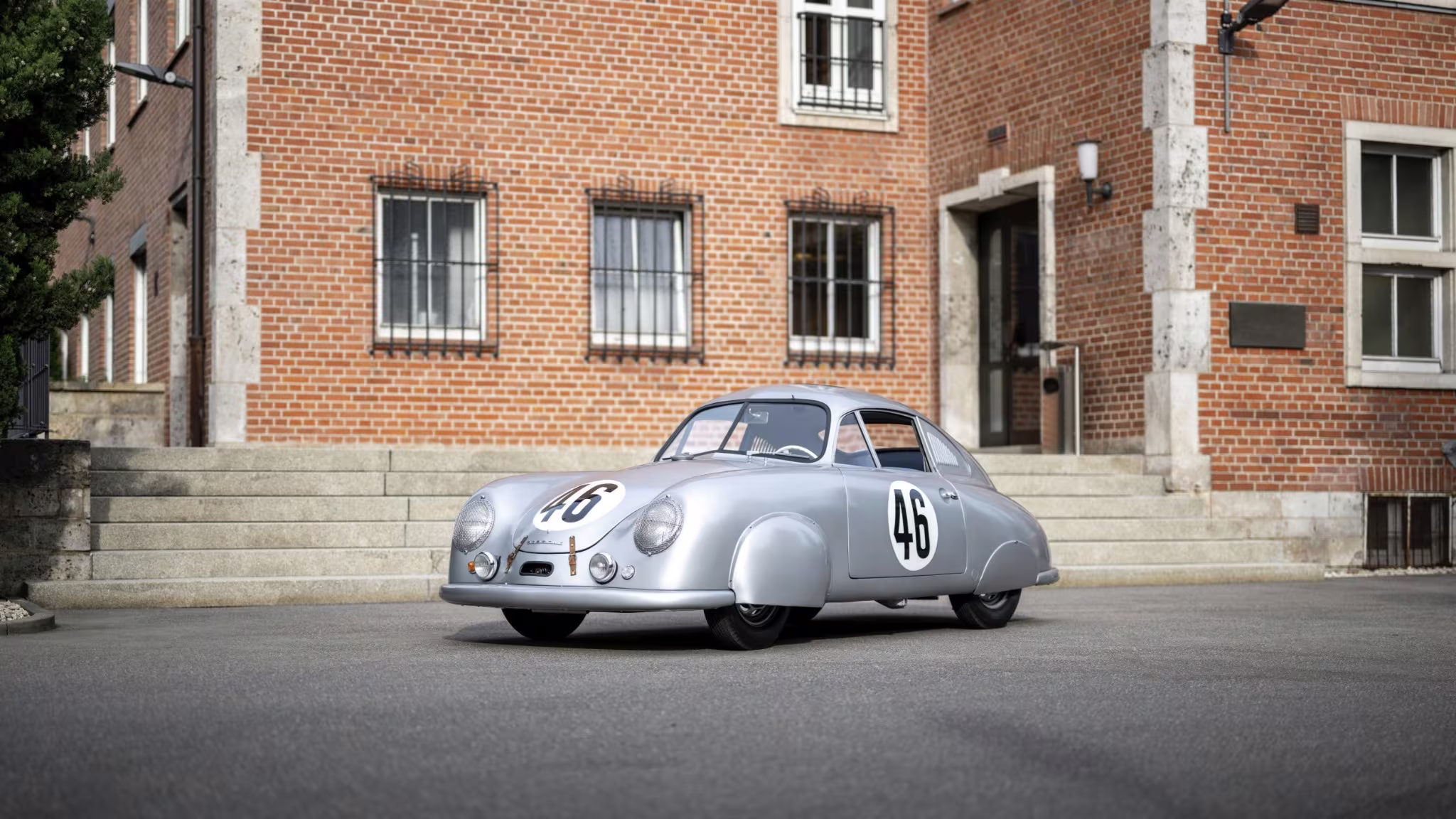 Porsche 356 SL número 46 em imagem externa diante de edifício histórico
