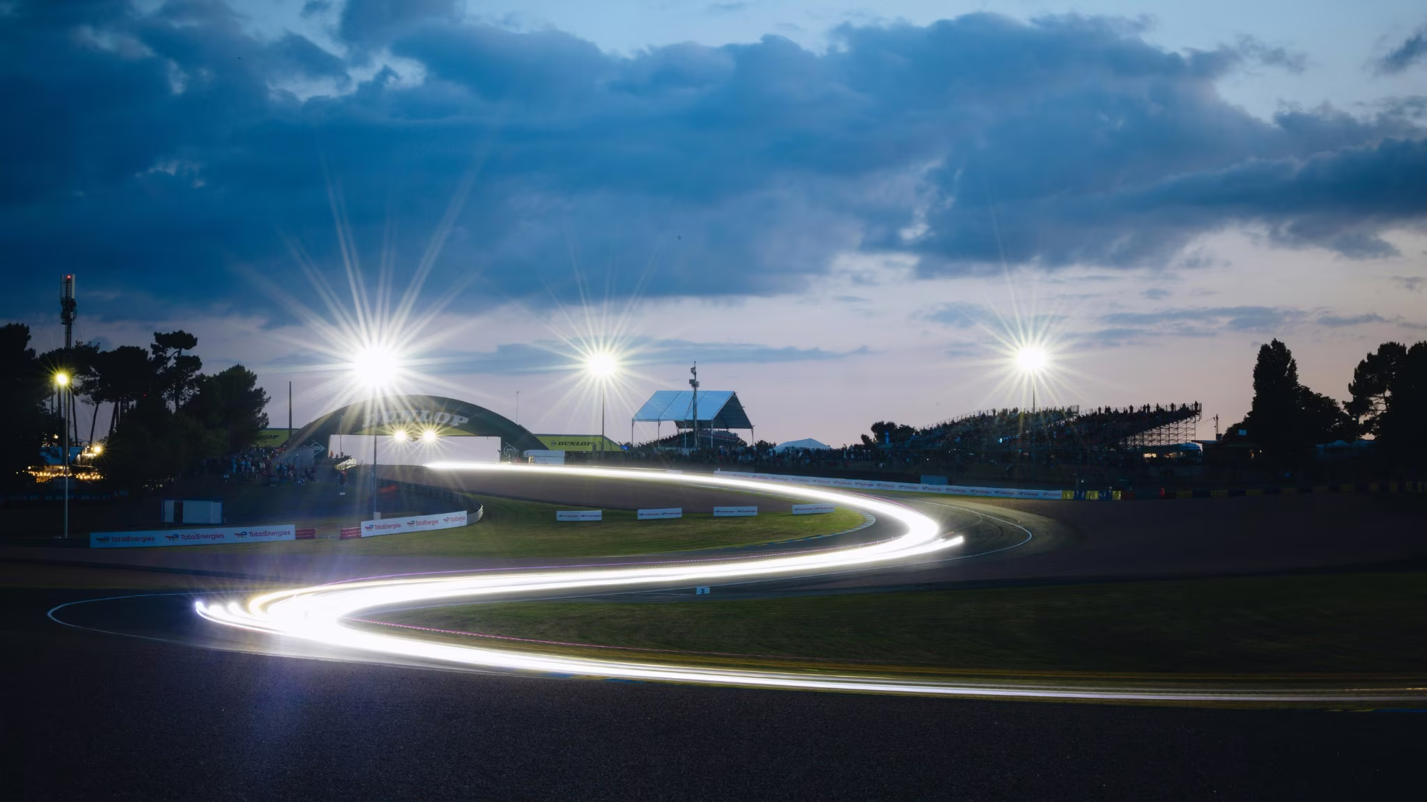 Trecho noturno do circuito de Le Mans com rastro de luz